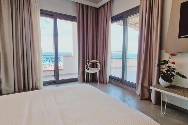 Camera con letto, tende e vista mare.