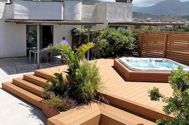 Jacuzzi su terrazza con piante e vista sui monti.