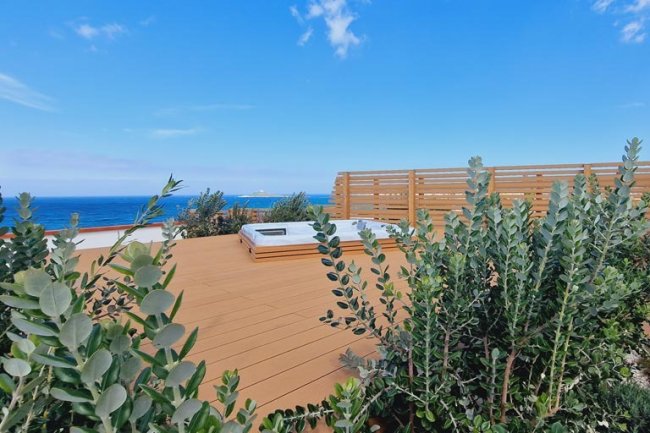 Terrazza con piante, vista mare e cielo azzurro.