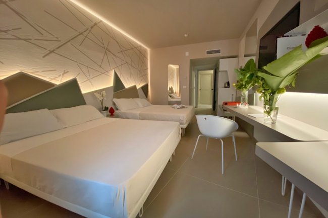 Camera d'hotel moderna con due letti matrimoniali.