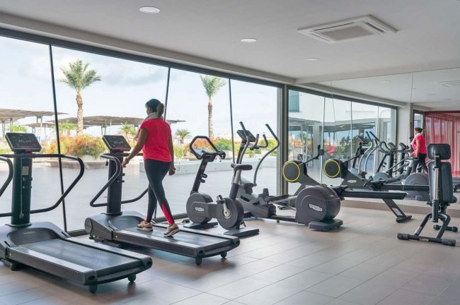 Palestra con attrezzature, persona su tapis roulant.