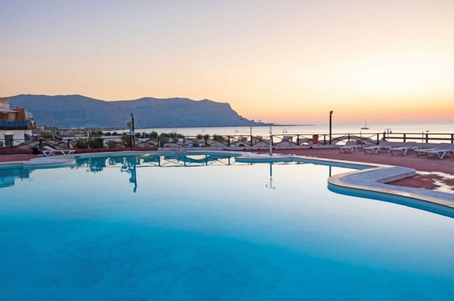 Piscina al tramonto con vista montagna e mare.