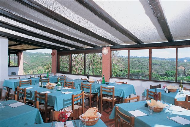 Sala da pranzo con tavoli apparecchiati e vista panoramica sulle colline.