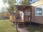 Una casa mobile con veranda e scale in legno su un prato verde.