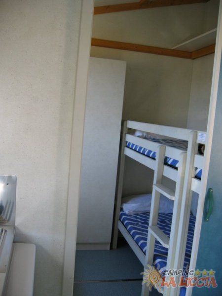 Letto a castello con lenzuola a righe blu e bianche in una piccola stanza.