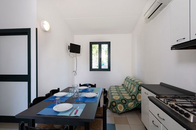 Cucina con tavolo apparecchiato e divano verde.