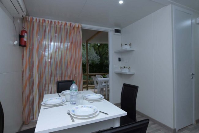 Sala da pranzo con tavolo apparecchiato e tende colorate.