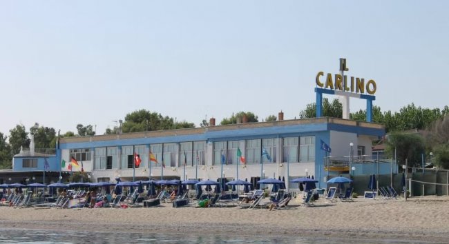 Edificio fronte mare con ombrelloni sulla spiaggia.