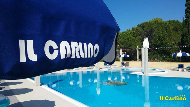 Una piscina con ombrelloni blu e bianchi.