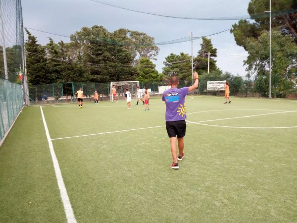 Partita di calcetto all'aperto con giocatori e arbitro.