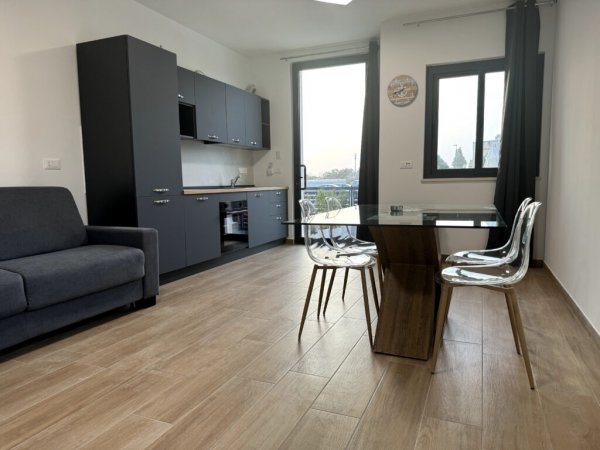 Interno moderno con cucina, tavolo e sedie trasparenti.