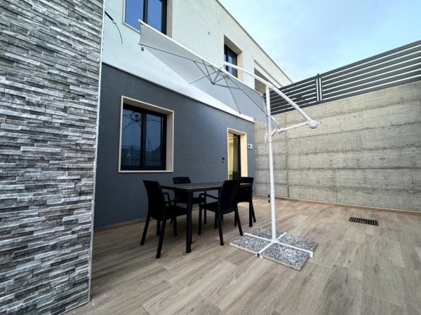 Patio con tavolo e ampio ombrellone.