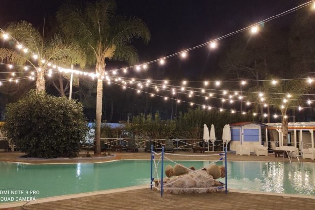 Piscina illuminata di sera con luci appese.