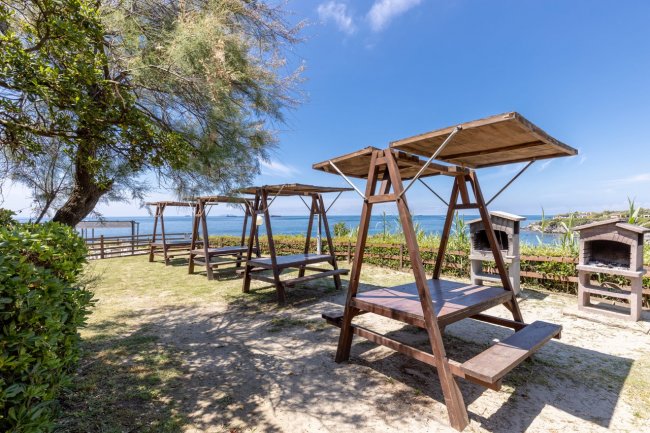 Tavoli in legno con tettoie vicino al mare.