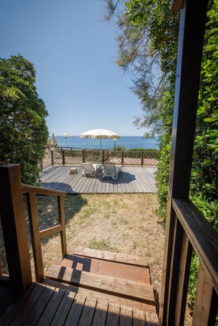 Terrazza fronte mare con lettini e ombrellone.