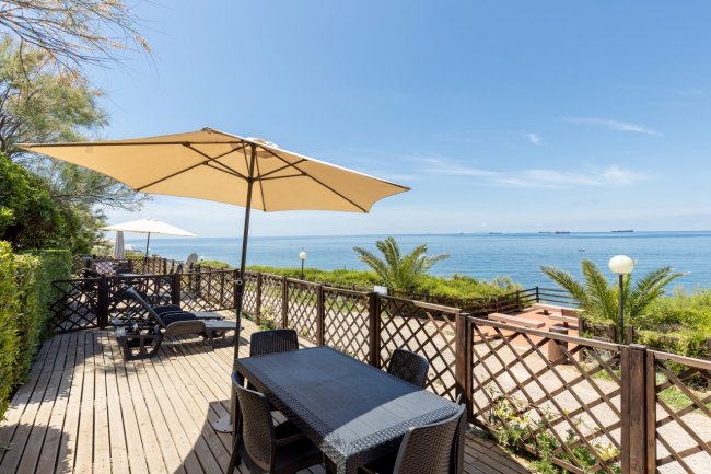 Terrazza con ombrelloni e sedie vista mare.
