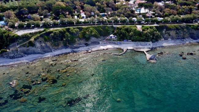 Vista aerea della costa rocciosa e acqua trasparente.