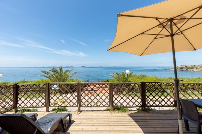 Vista mare da una terrazza con sedie e ombrellone.