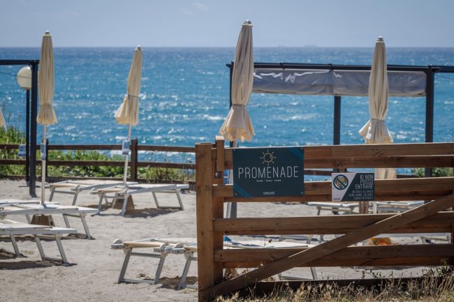 Spiaggia con lettini e ombrelloni chiusi, vista mare.