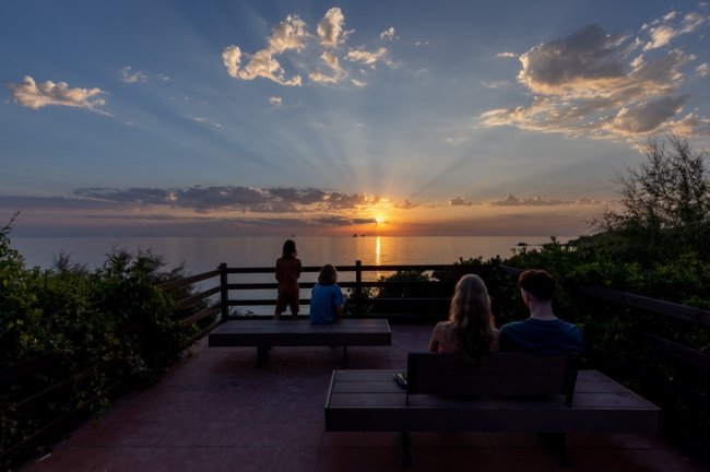 Tramonto sul mare con tre persone.