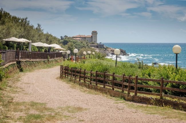 Sentiero costiero con lampioni e vista su un promontorio.