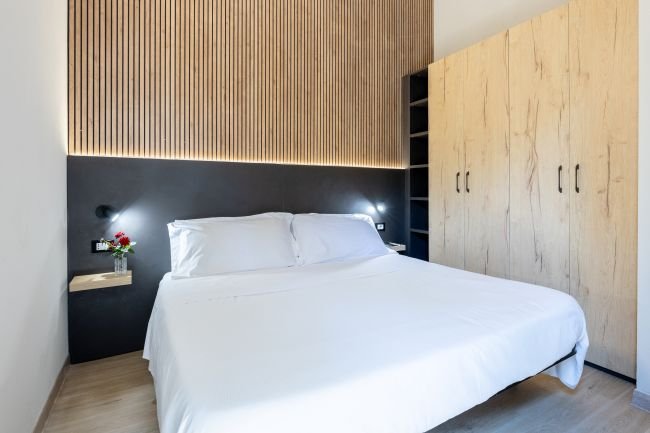 Letto matrimoniale in una camera moderna con parete in legno.