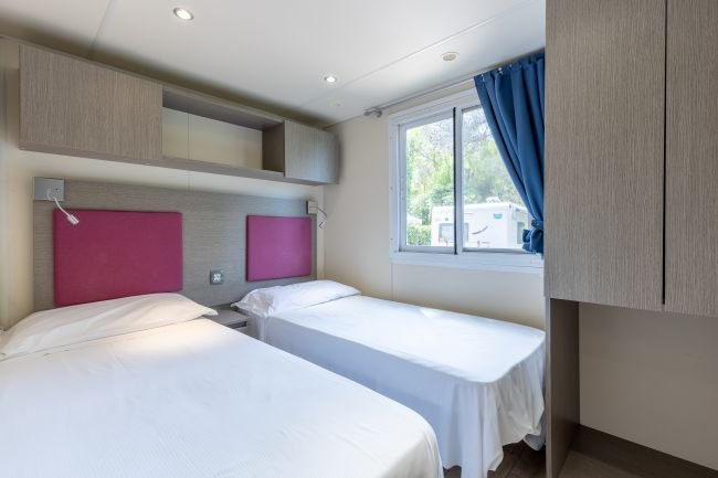 Due letti singoli in una camera con testiere rosse e finestra.