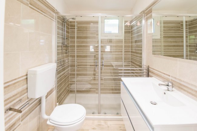 Un bagno con doccia con porte in vetro, lavabo moderno e wc sospeso.