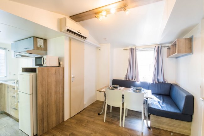 Cucina e sala da pranzo in stile moderno, con tavolo apparecchiato, divano e cucina compatta.