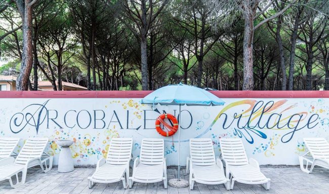 Lettini bianchi e ombrellone davanti a un colorato muro 