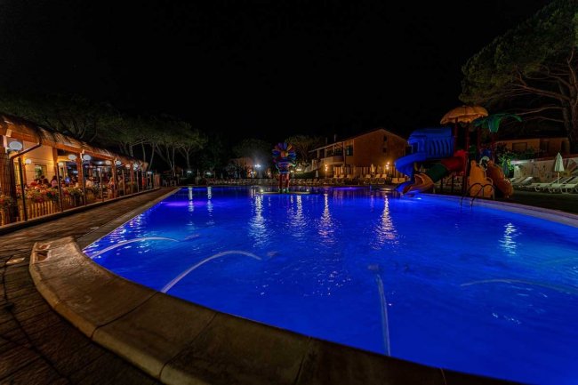 Piscina illuminata di notte con giochi d'acqua.