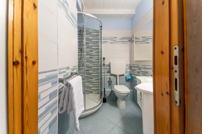 Bagno moderno con doccia ad angolo e piastrelle decorative blu e bianche.
