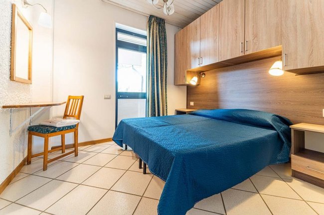 Camera da letto con letto matrimoniale, sedia e tavolo vicino alla finestra.