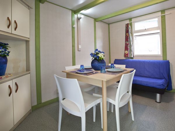 Tavolo da pranzo con sedie bianche, divano blu e vasi di fiori all'interno.
