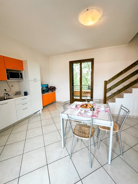 Cucina e sala da pranzo con scala e tavolo apparecchiato.