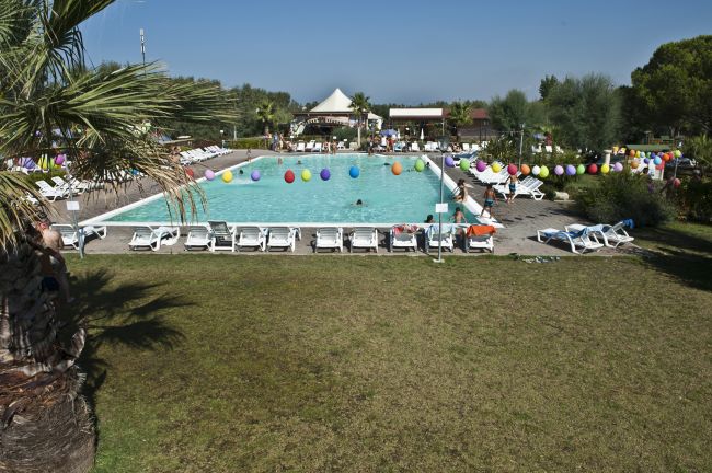Piscina all'aperto circondata da lettini e decorata con palloncini colorati.