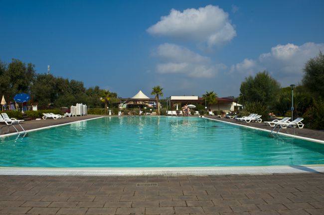 Piscina all'aperto con lettini e cielo azzurro.