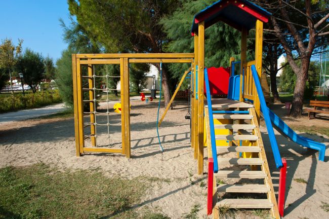 Vicino di un parco giochi con scivolo blu e strutture in legno.