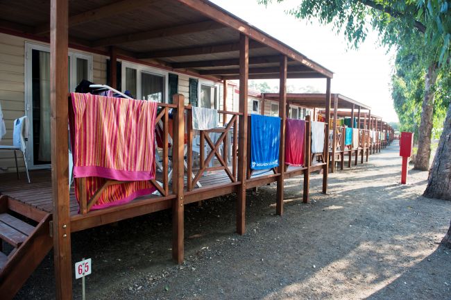 Bungalow con terrazze in legno, asciugamani colorati appesi alle ringhiere.