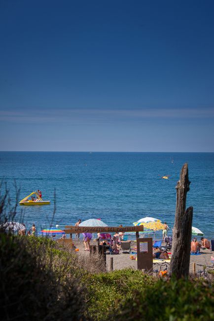 Una spiaggia con ombrelloni colorati e persone in acqua.