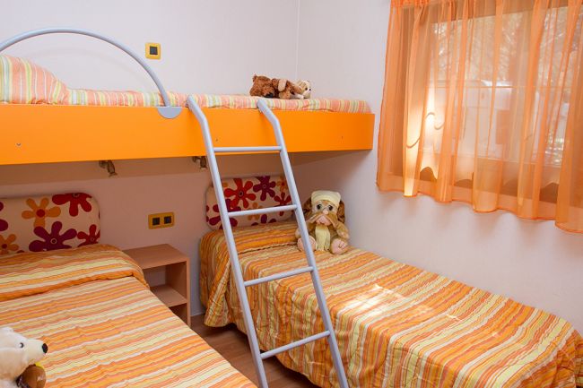 Cameretta con letti a castello arancioni e peluche.