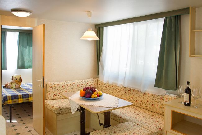 Angolo pranzo con frutta su tavolo e letto sullo sfondo.