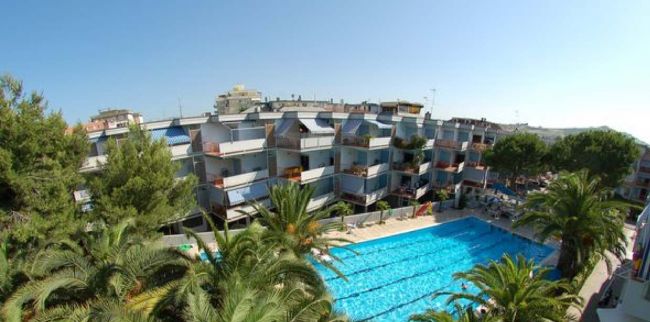 Complesso di appartamenti moderni con una grande piscina circondata da palme.