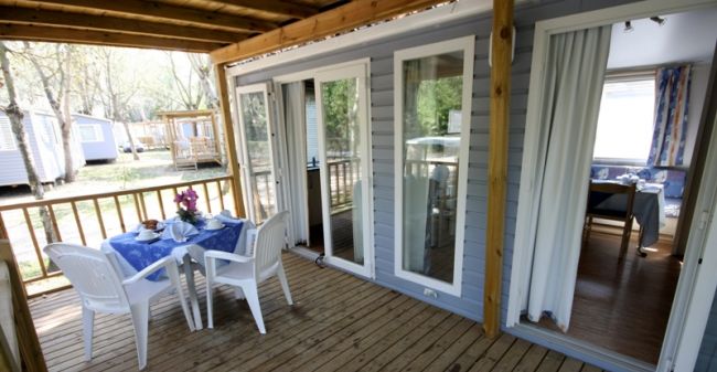 Veranda in legno con tavolo apparecchiato.