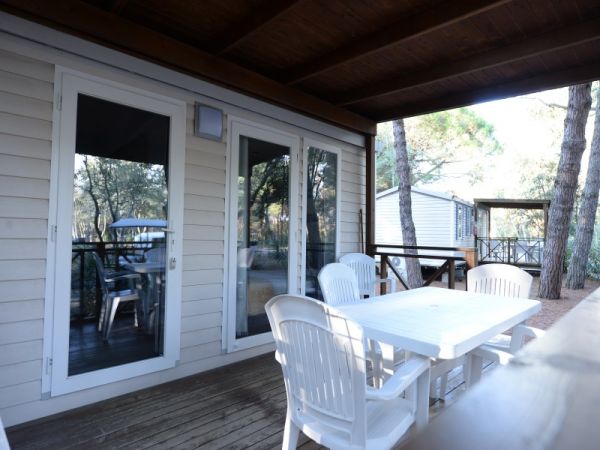 Veranda esterna con tavolo e sedie bianche.