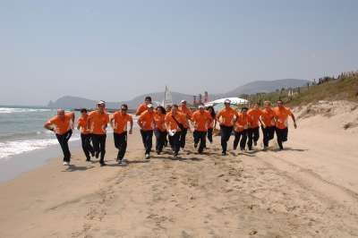 Gruppo di persone in tuta arancione corre sulla spiaggia vicino al mare.