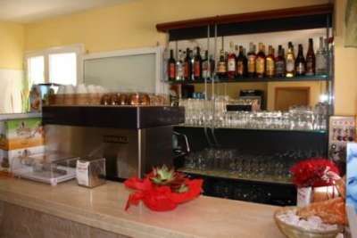 Dettaglio del bancone bar con macchina da caffè e scaffale di liquori.