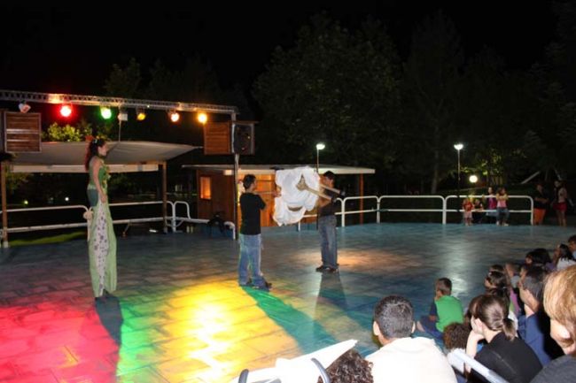 Persone si esibiscono su un palco illuminato di notte.