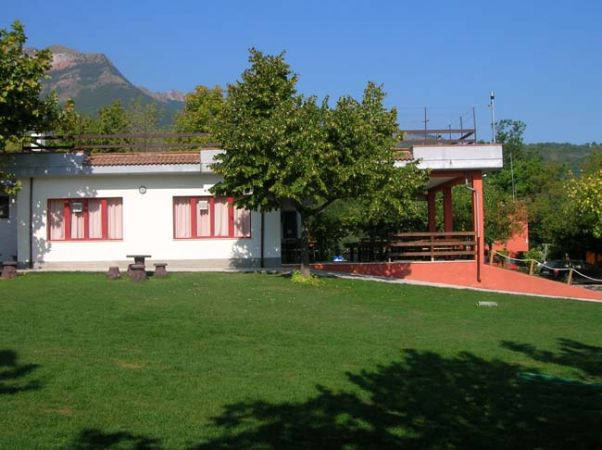 Edificio bianco con tetto piano e prato verde. Alberi intorno.