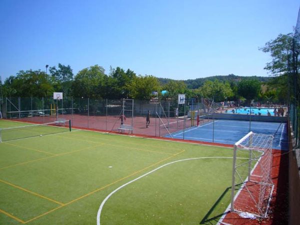 Un campo sportivo all'aperto con porte da calcio e canestri, vicino a una piscina.